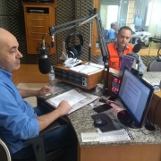 Duas pessoas sentadas, em um estúdio de rádio.