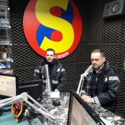 Duas pessoas sentadas, num estúdio de uma radio, prestando entrevista.