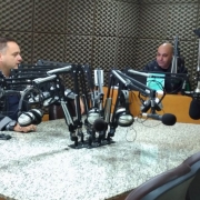 Duas pessoas sentadas em um estúdio de uma radio.