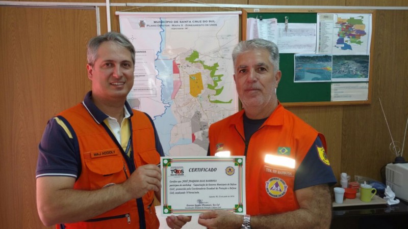 Dois homens posam segurando um certificado de papel