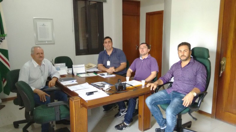 um escritório com quatro pessoas sentadas em volta de uma mesa de trabalho