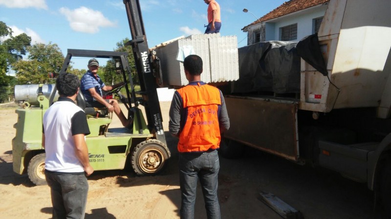 dois homens observando uma máquina colocar um monte de telha dentro de um caminhão