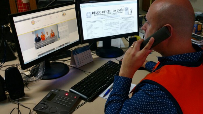 Representante da Defesa Civil falando no telefone, analisando documentações