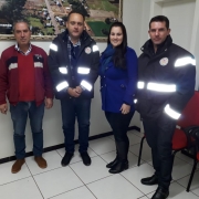 Quatro pessoas em pé com roupas escuras.