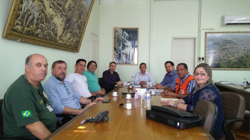 Muitas pessoas juntas, sentados na numa mesa em volta tem parede cor verde com quadros