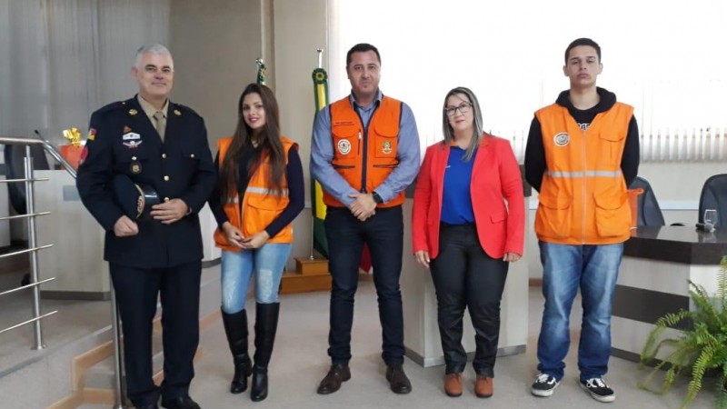 Cinco pessoas em pé com roupas laranjas