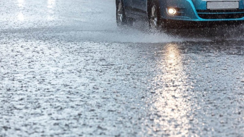 Chuva intensa e carro azul ao fundo.