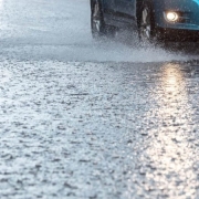 Chuva intensa e carro azul ao fundo.