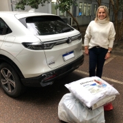 Rosane posa ao lado de seu carro com suas doações ao chão