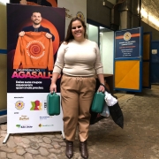 Otavia ao lado do cartaz da Campanha do Agasalho entrega doações