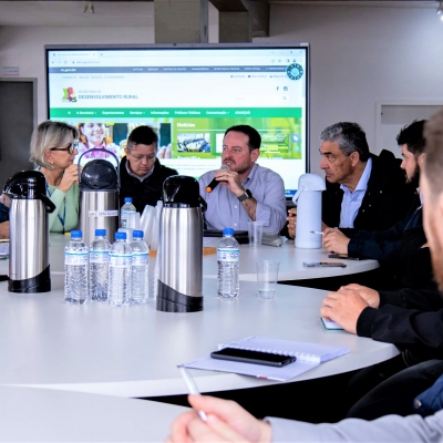 Imagem de várias pessoa sentadas à mesa em reunião.