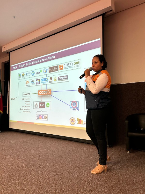 Representante da Defesa Civil Estadual utiliza recurso digital para apresentar o conteúdo à plateia