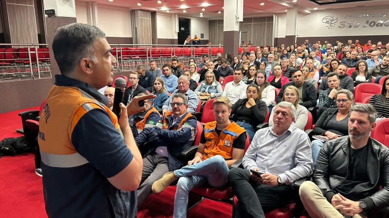 Representante da Defesa Civil Estadual palestra para pessoas reunidas em um auditório