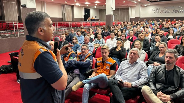 Representante da Defesa Civil Estadual palestra para pessoas reunidas em um auditório