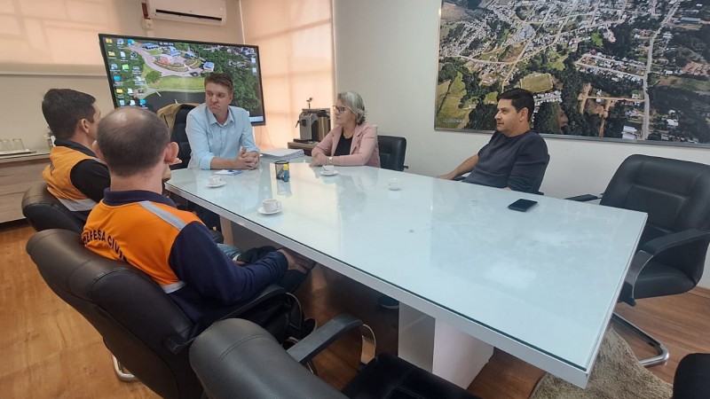 mesa de reunião com 4 homens e 1 mulher