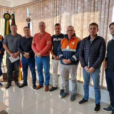 Oito homens parados para a foto com escarapelas ao fundo 