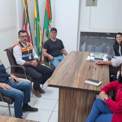 5 homens e 2 mulheres sentados ao redor de uma mesa em reunião