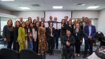 Representantes dos &oacute;rg&atilde;os que assinam o acordo de coopera&ccedil;&atilde;o posam para a foto juntos, mostrando o acordo
