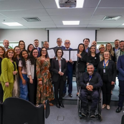 Representantes dos &oacute;rg&atilde;os que assinam o acordo de coopera&ccedil;&atilde;o posam para a foto juntos, mostrando o acordo